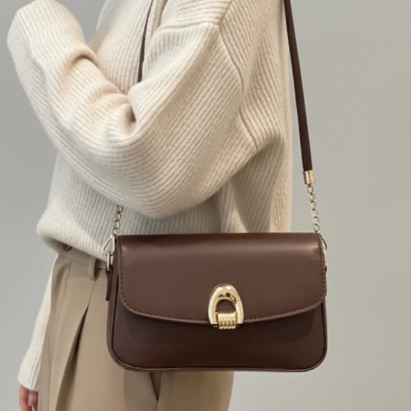 Modelo usando a bolsa baguete marrom no ombro. A imagem realça o estilo elegante e o formato compacto do acessório.