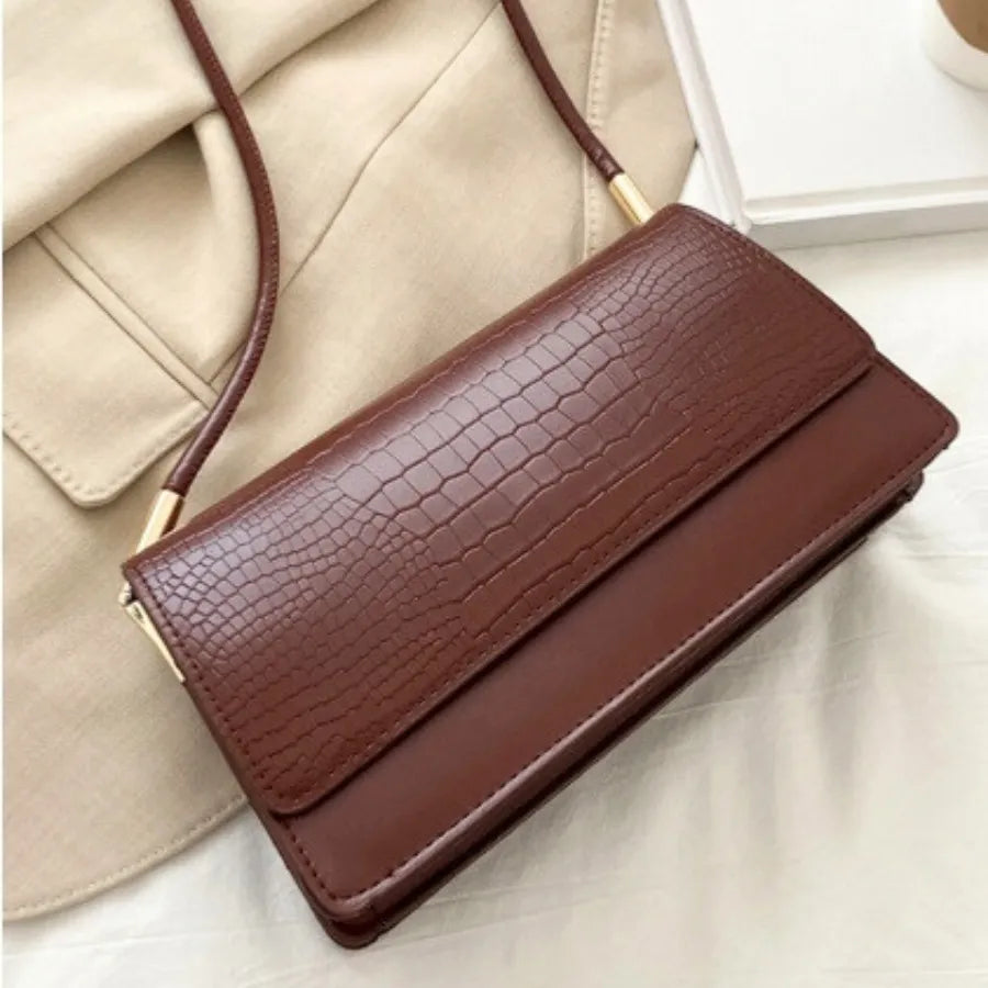 Detalhe da textura croco da bolsa de ombro marrom Baguette da Rozze. A foto aproxima o material em couro PU de alta qualidade e o padrão texturizado.