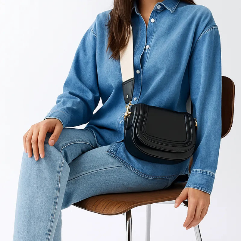 Modelo usando a bolsa de ombro Florence da Rozze, sentada. A imagem mostra o acessório em uso, com foco na alça removível e no fechamento por ferrolho.