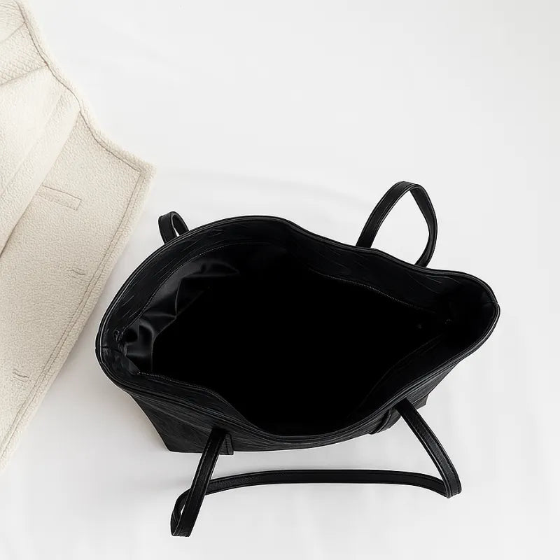 Vista superior da bolsa tote preta aberta. A foto revela o interior espaçoso, ideal para o dia a dia, e o fechamento com fivela.