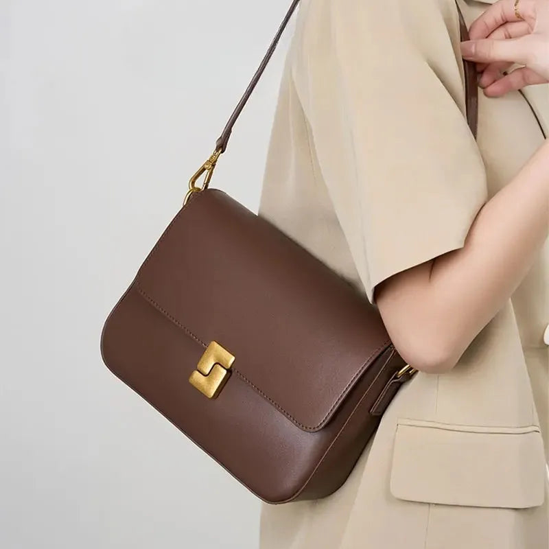 Modelo usando a bolsa transversal Prestige, vista de perfil. A imagem mostra a bolsa em uso, realçando sua forma compacta e o estilo elegante.