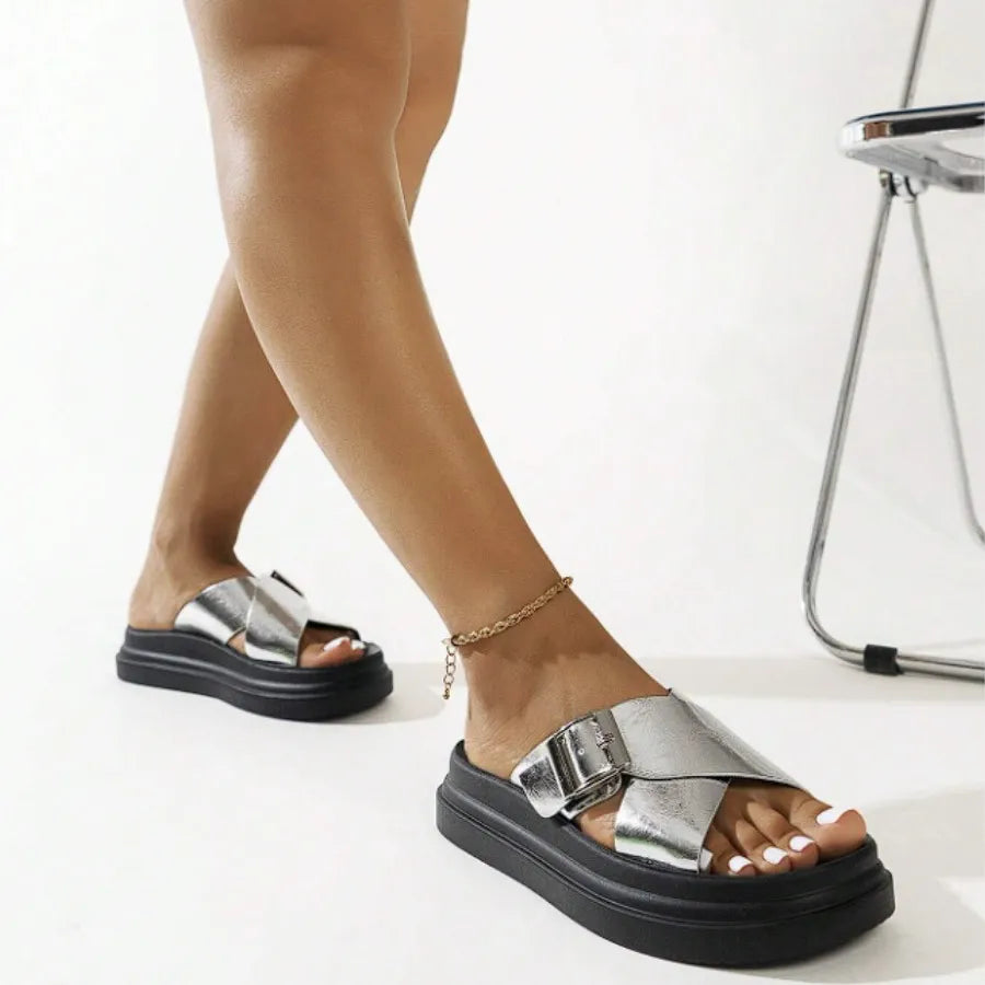Vista traseira da modelo usando a papete feminina prata de fivela da Rozze. A foto destaca o solado preto e o design moderno do acessório.