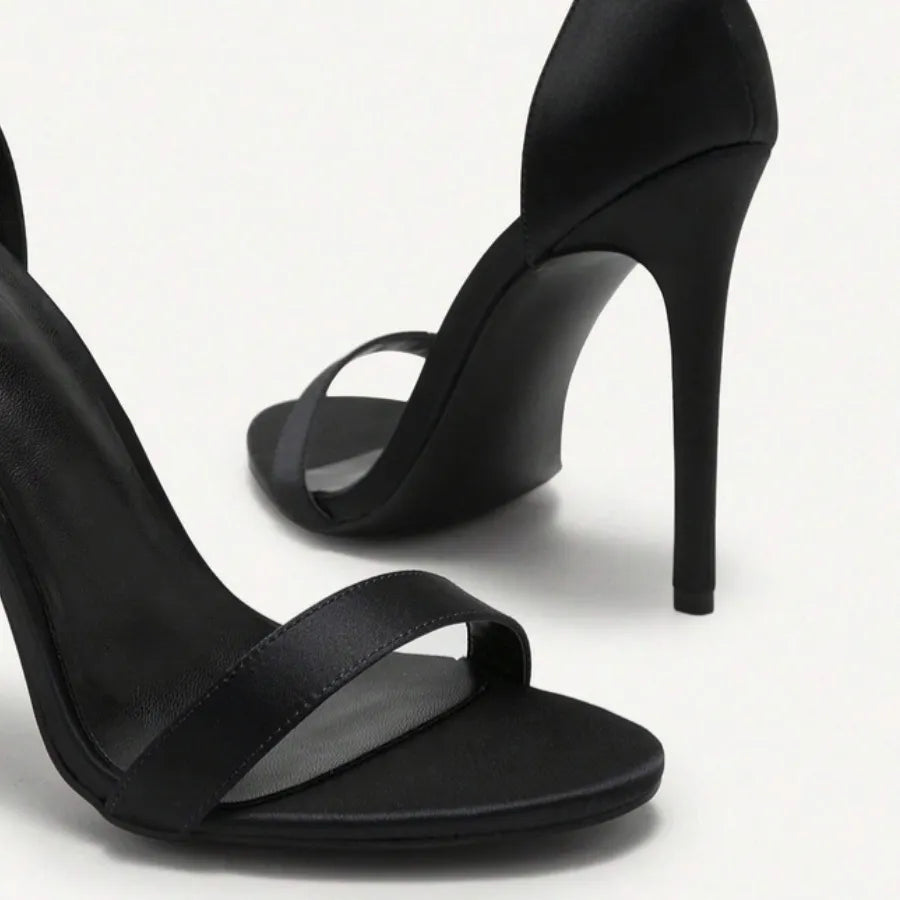 Par de sandálias de salto alto Juliet da Rozze, em vista lateral. A foto em estúdio destaca a forma do calçado, o material de camurça premium e o salto agulha.