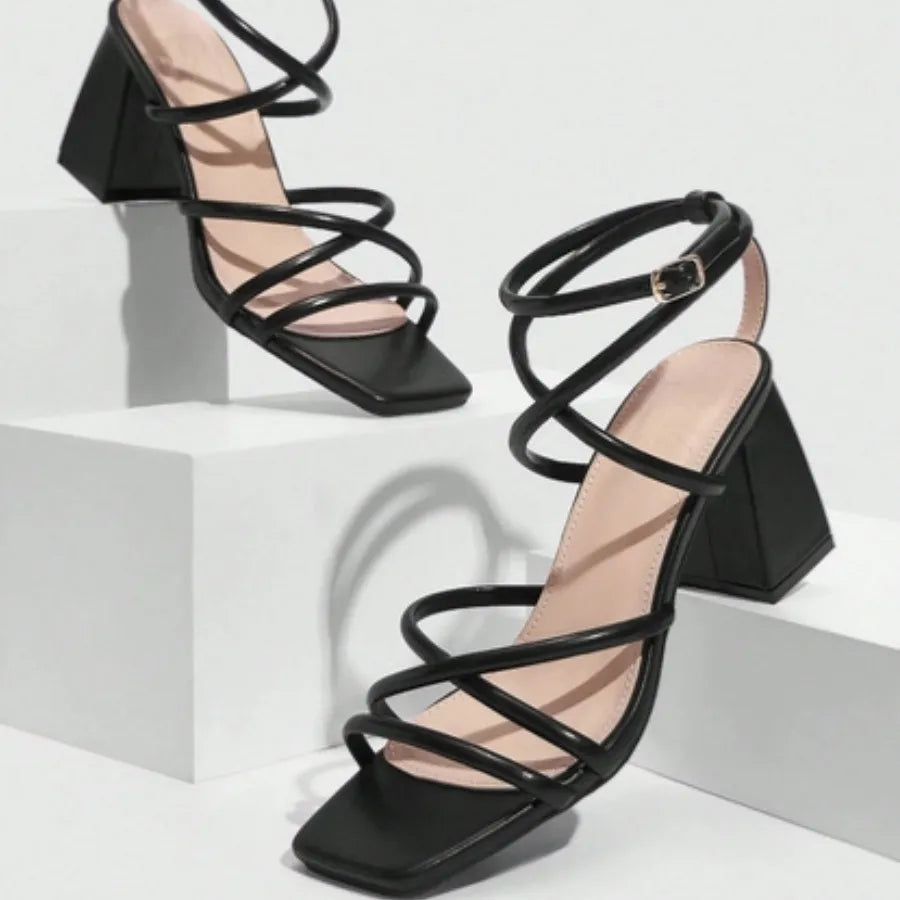 Modelo usando a sandália preta de tiras cruzadas da Rozze. A imagem mostra o calçado em uso, exibindo como as tiras se ajustam e o conforto proporcionado pelo salto chunky.