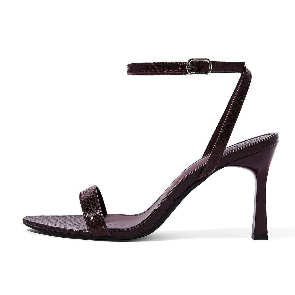 Sandália feminina vinho de salto agulha, vista lateral em estúdio. A foto destaca a estampa croco, a tira no tornozelo e o salto de 9 cm.