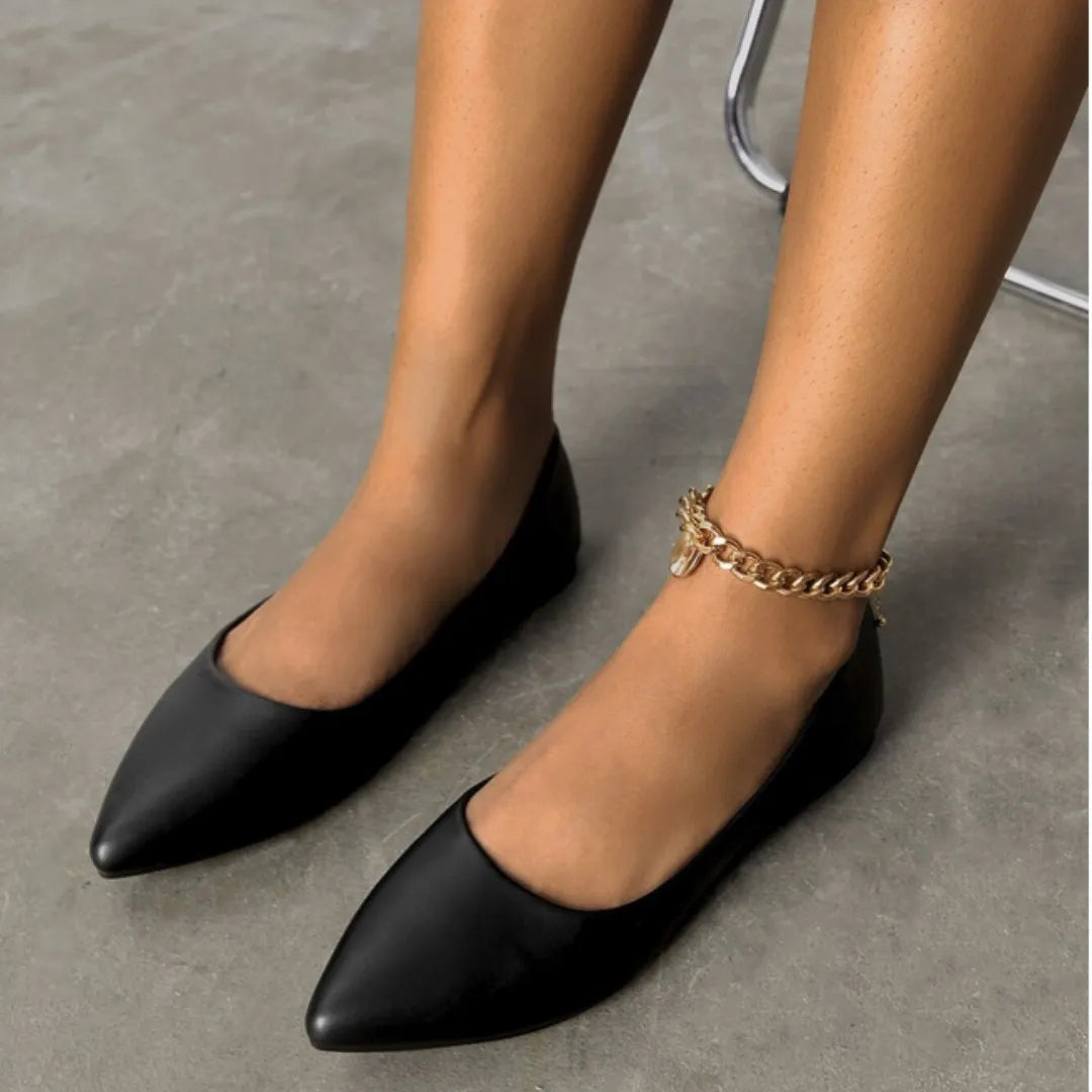 Modelo usando a sapatilha feminina preta de bico fino da Rozze, em pé. A imagem mostra o calçado em uso, complementando um look casual e elegante com calça jeans.