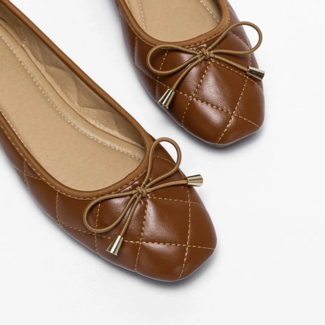 Par de sapatilhas marrons acolchoadas com laço da Rozze, em vista de ângulo. A foto em estúdio destaca o design confortável e o laço sofisticado.