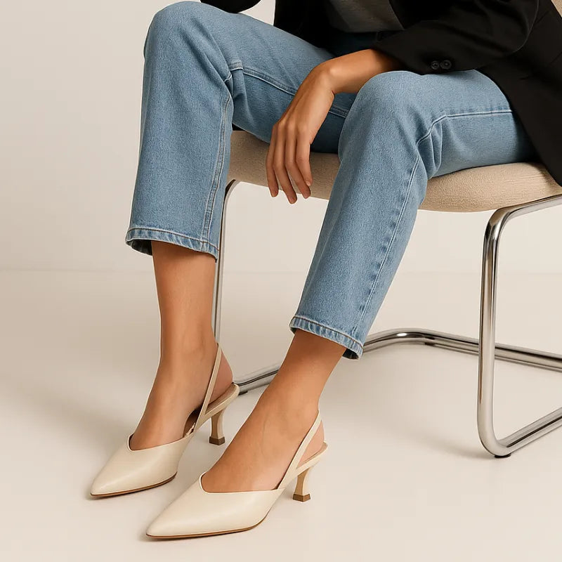 Modelo usando o scarpin marfim slingback da Rozze, sentada. A imagem mostra o calçado em uso, complementando um look casual com calça jeans e blazer.