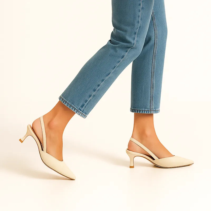 Vista de perfil da modelo usando o scarpin marfim slingback da Rozze. A foto realça a silhueta do calçado no pé, combinando com calça jeans de barra dobrada.