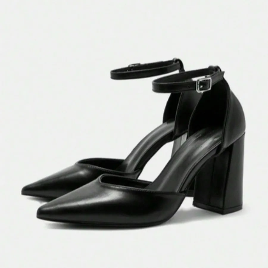 Par de scarpins pretos com tira no tornozelo da Rozze. A foto em estúdio destaca o design moderno com bico fino, o salto chunky e o acabamento do material de poliuretano de alta qualidade.