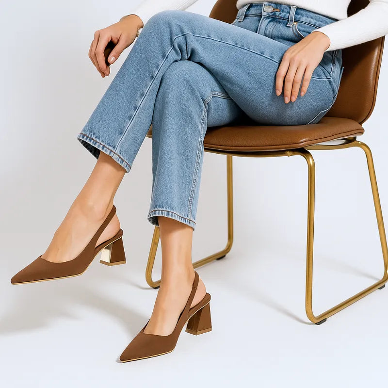 Modelo usando o scarpin slingback marrom da Rozze, sentada. A imagem mostra o calçado em uso, complementando um look casual com calça jeans.