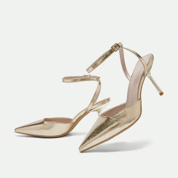 Scarpin dourado slingback bico fino em vista frontal, com bico, tiras e formato do par visíveis, sobre fundo claro