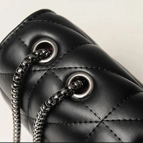 Bolsa acolchoada preta com alça de corrente em vista superior, exibindo textura acolchoada e alça.