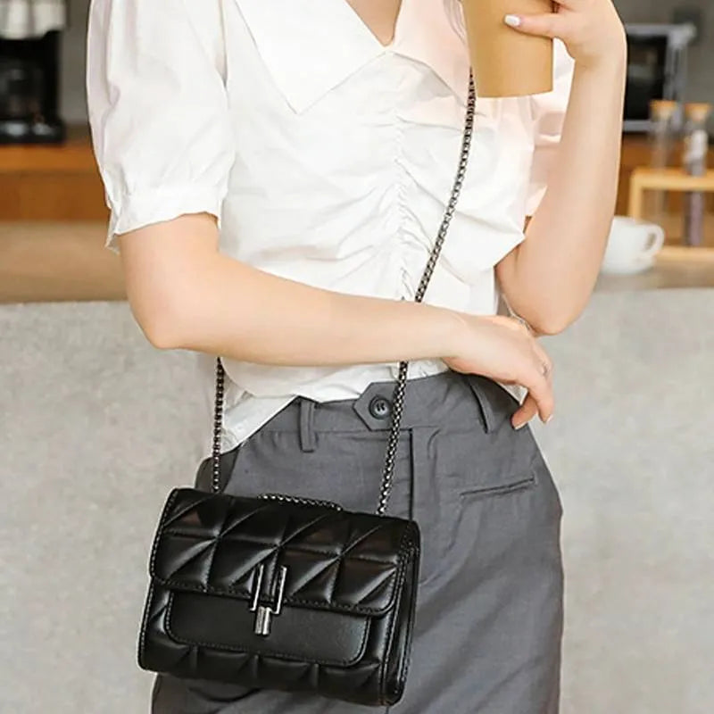 Modelo usando a bolsa acolchoada preta como crossbody. A imagem mostra o acessório em uso, com a alça de corrente longa, ideal para o dia a dia.
