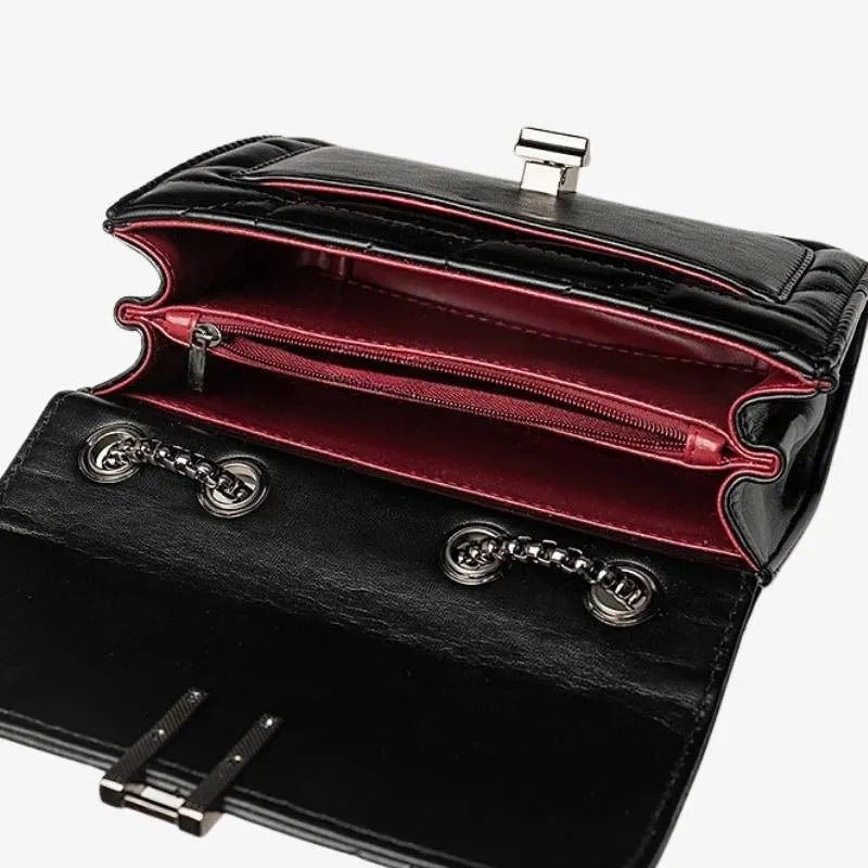 Detalhe da alça de corrente da bolsa acolchoada preta. Foco nos ilhós e na junção da alça, demonstrando a versatilidade de uso como bolsa de ombro ou crossbody.
