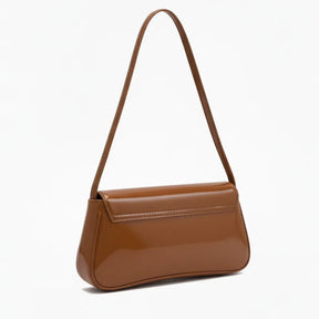 Bolsa baguete caramelo verniz em vista lateral. A imagem exibe a forma do acessório e o brilho do material, ideal para looks noturnos.