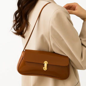 Modelo usando a bolsa baguete caramelo no ombro. A imagem realça o estilo elegante e o tamanho compacto do acessório.