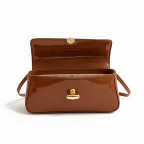 Vista superior da bolsa baguete caramelo aberta. A foto revela o interior e o encaixe metálico do fecho, mostrando o design sofisticado.