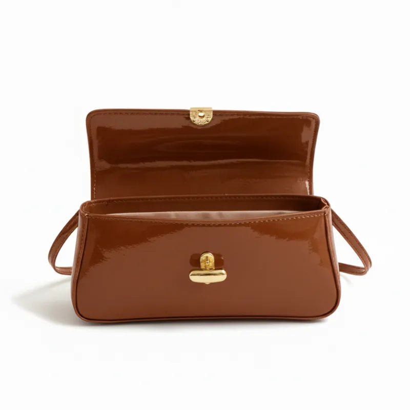 Vista superior da bolsa baguete caramelo aberta. A foto revela o interior e o encaixe metálico do fecho, mostrando o design sofisticado.