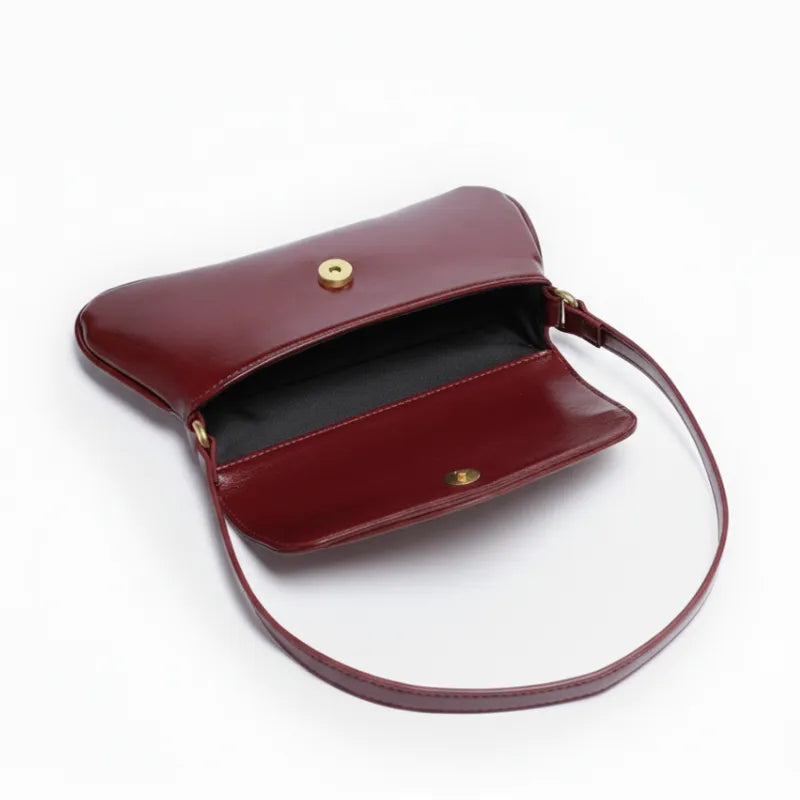 Vista superior da bolsa baguete marsala aberta. A foto revela o interior e a estrutura da bolsa, mostrando a funcionalidade.