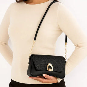 Modelo usando a bolsa baguete preta no ombro. A imagem realça o estilo de festa e o brilho do acessório em um look noturno.