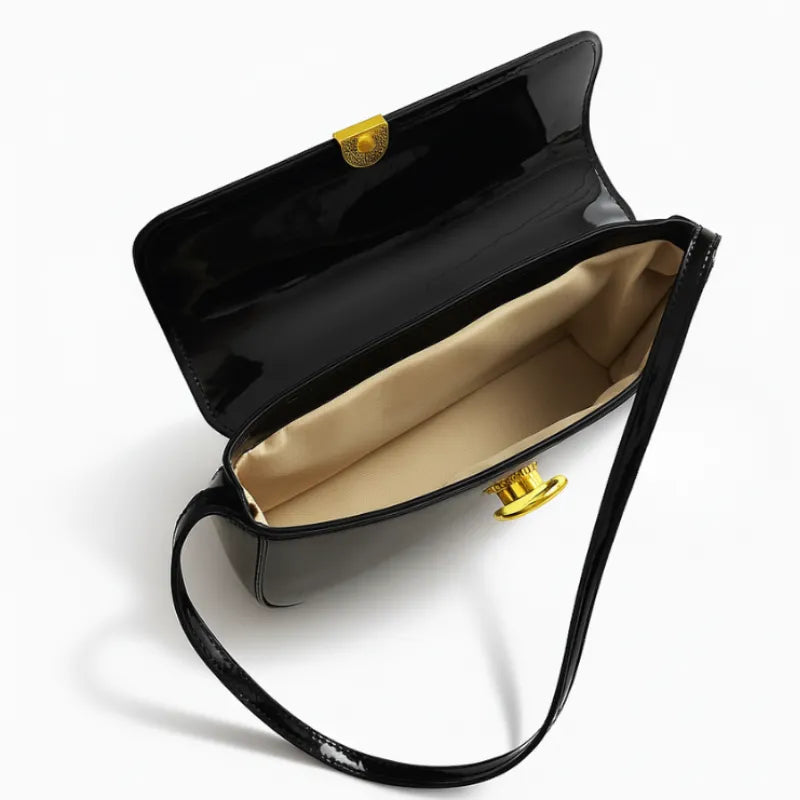 Modelo usando a bolsa baguete preta no ombro. A imagem realça o estilo elegante e o brilho do material em um look noturno.