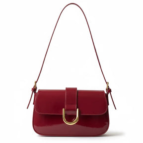 Bolsa baguete feminina vermelho verniz, vista frontal. A foto destaca o brilho do material e a fivela dourada em formato de D.