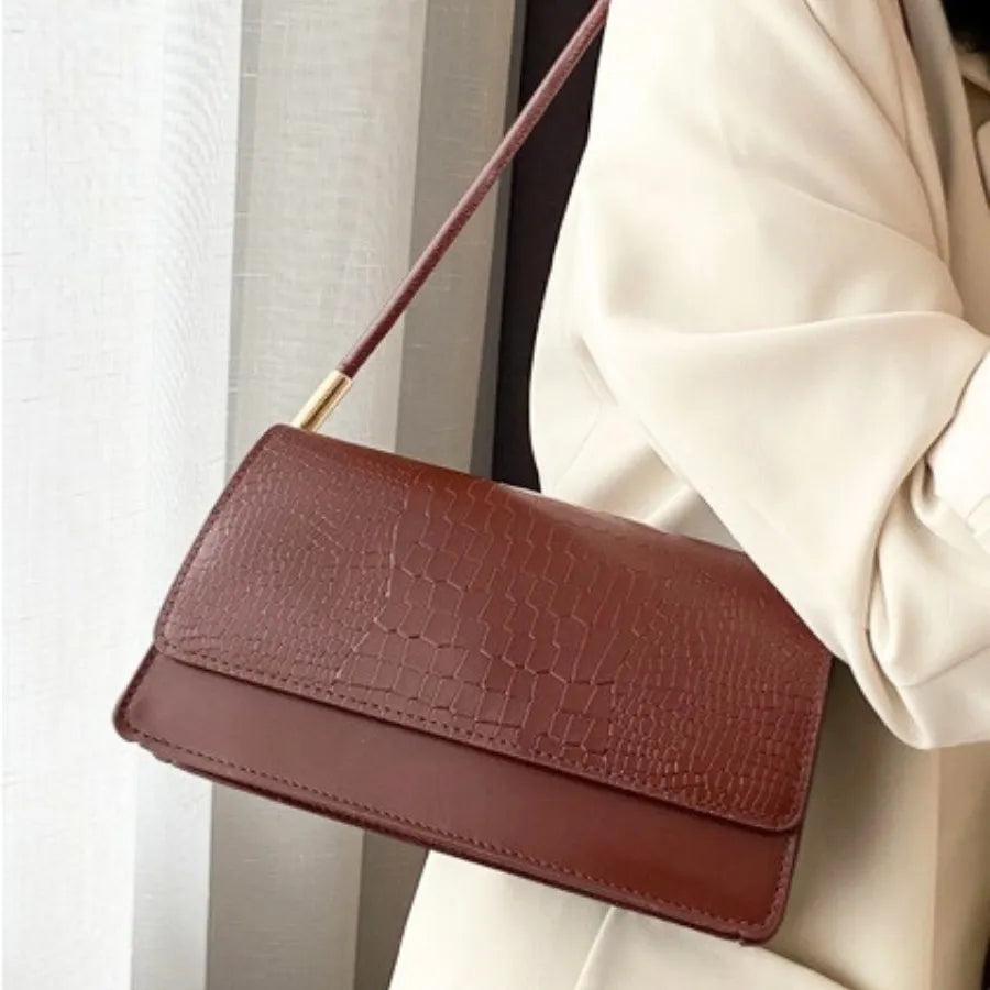 Modelo usando a bolsa de ombro marrom Baguette Croc da Rozze. A imagem mostra o acessório a tiracolo, exibindo seu tamanho compacto e estilo elegante para o dia a dia.