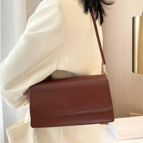 Modelo usando a bolsa de ombro marrom Baguette Croc da Rozze, em um close. A foto realça o material em couro PU com estampa texturizada e o design minimalista.