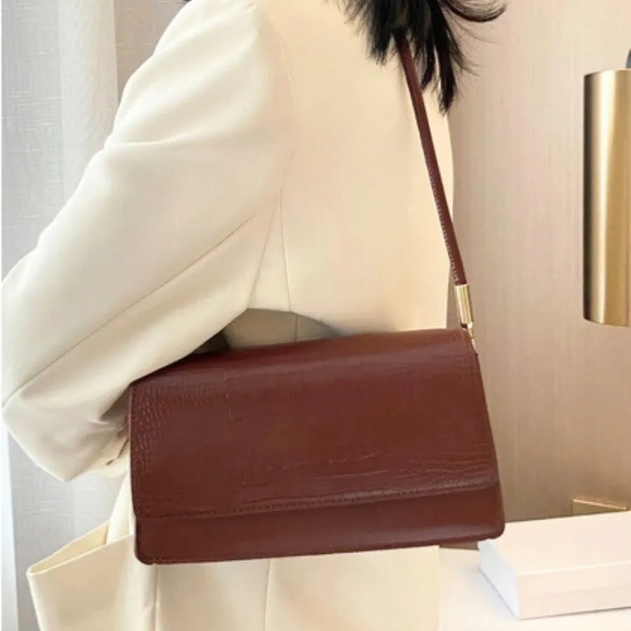 Modelo usando a bolsa de ombro marrom Baguette Croc da Rozze, em um close. A foto realça o material em couro PU com estampa texturizada e o design minimalista.