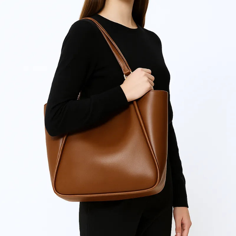 Modelo usando a bolsa de ombro marrom. A imagem mostra o acessório sendo carregado no ombro, realçando seu visual Minimalista e praticidade.