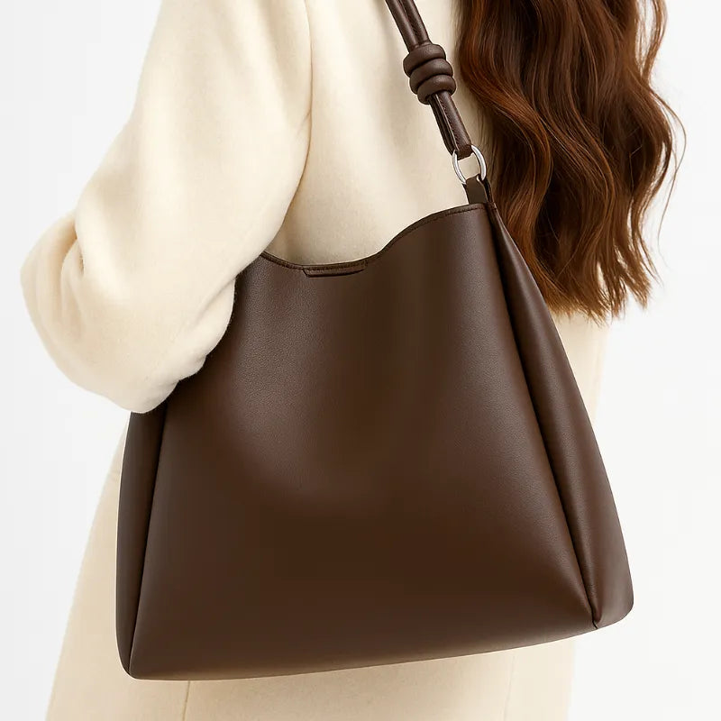 Modelo usando a bolsa de ombro marrom. A imagem mostra o acessório sendo carregado, realçando o estilo Elegante e a alta capacidade da bolsa.