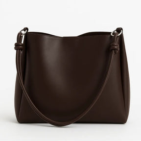 Bolsa de ombro marrom em vista frontal. A foto exibe a bolsa na sua forma macia e o material em Couro PU com Padrão Texturizado.