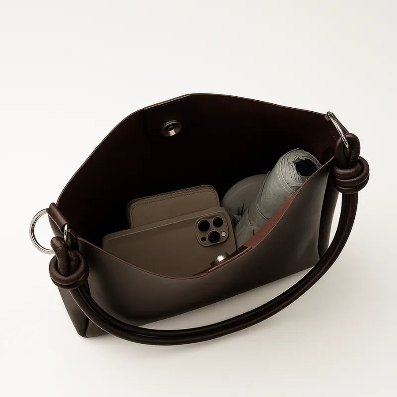 Vista superior da bolsa de ombro marrom aberta. A foto revela o interior com fechamento por Zíper e o espaço interno, ideal para os essenciais.