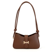 Bolsa de ombro feminina marrom, vista frontal em estúdio. A foto destaca o formato baguette e o fecho de barra metálica dourada.