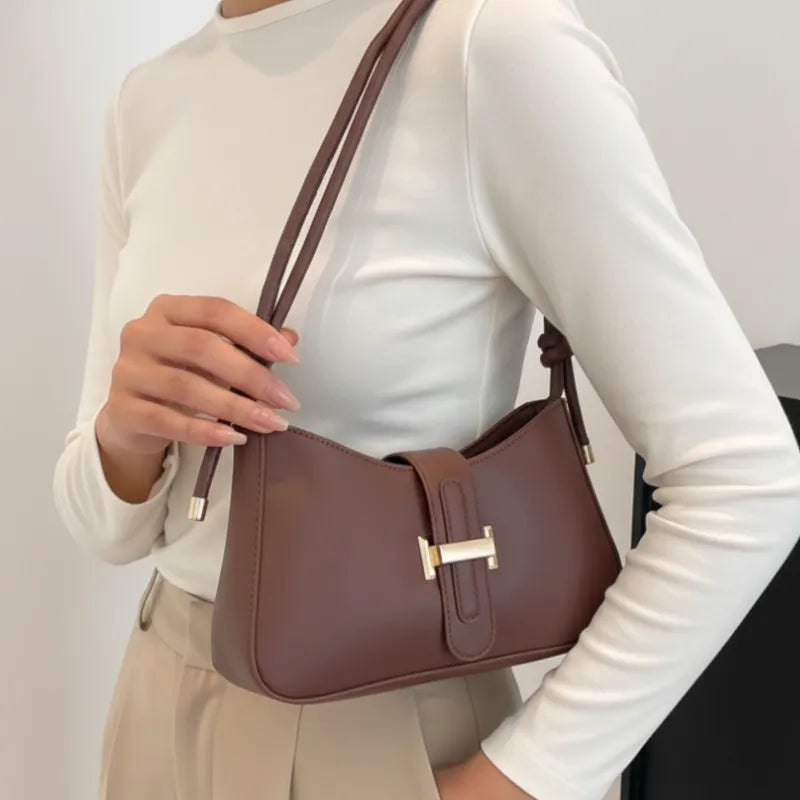 Modelo usando a bolsa de ombro marrom. A imagem realça o estilo elegante e a alça de ombro com detalhe de nó.