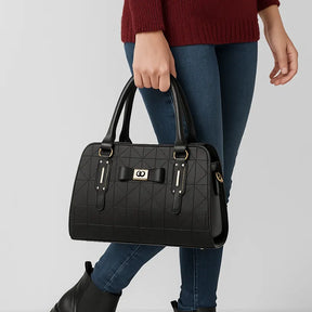 Modelo usando a bolsa de ombro preta Charme Clássico da Rozze, em pé. A foto realça a versatilidade do acessório, que pode ser usado tanto a tiracolo quanto na mão.