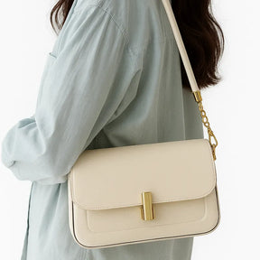 Modelo usando a bolsa retangular branca no ombro. A imagem realça o estilo elegante e o tamanho compacto do acessório.