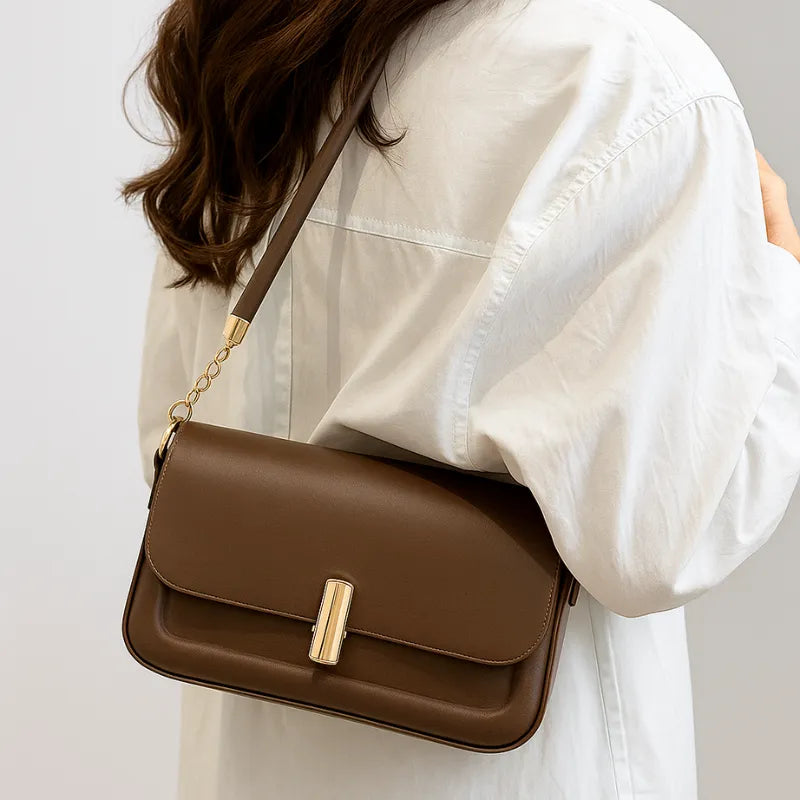 Modelo usando a bolsa retangular marrom no ombro. A imagem realça o estilo elegante e o tamanho compacto do acessório.