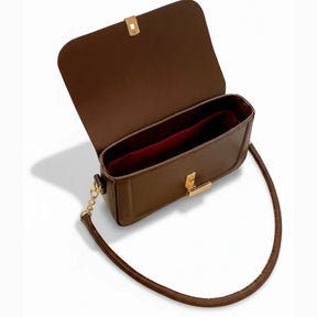 Vista superior da bolsa retangular marrom aberta. A foto revela o interior com forro avermelhado e o espaço interno para essenciais.