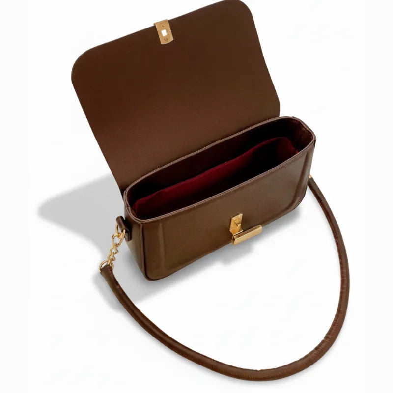 Vista superior da bolsa retangular marrom aberta. A foto revela o interior com forro avermelhado e o espaço interno para essenciais.