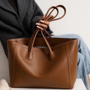 Vista da bolsa tote caramelo com o topo cinzado por amarração. A imagem destaca a versatilidade do fechamento e o visual elegante.