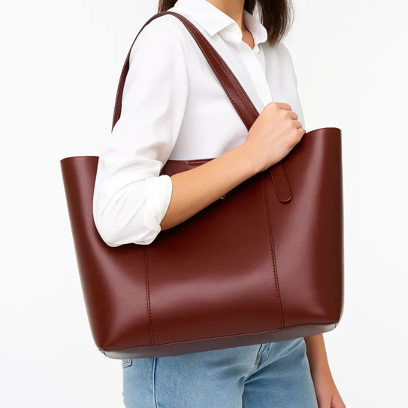 Modelo usando a bolsa tote marrom no ombro. A imagem mostra o acessório em uso, realçando seu tamanho e o estilo sofisticado para o dia a dia.