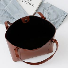 Vista superior da bolsa tote marrom aberta. A foto revela o interior espaçoso, ideal para carregar itens de trabalho ou compras.