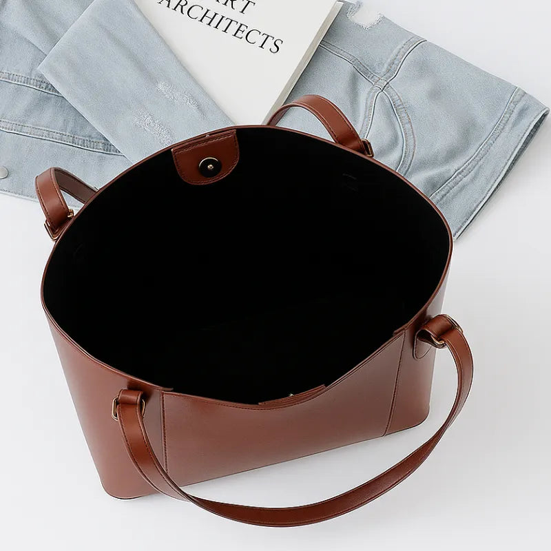 Vista superior da bolsa tote marrom aberta. A foto revela o interior espaçoso, ideal para carregar itens de trabalho ou compras.