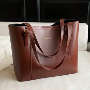 Bolsa tote marrom em vista frontal. A foto exibe a forma do acessório e a estrutura semi-rígida, que mantém a elegância.