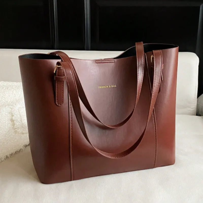 Bolsa tote marrom em vista frontal. A foto exibe a forma do acessório e a estrutura semi-rígida, que mantém a elegância.