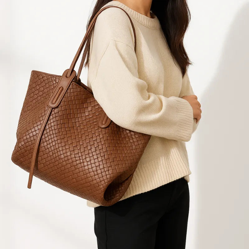 Modelo usando a bolsa tote marrom tramada. A imagem mostra o acessório sendo carregado no ombro, realçando seu tamanho e o design elegante.