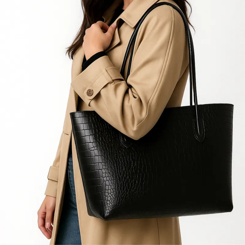 Modelo usando a bolsa tote preta de croco. A imagem mostra o acessório sendo carregado no ombro, realçando seu tamanho e elegância para o dia a dia