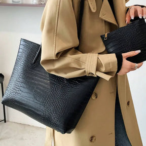 Modelo em movimento usando a bolsa tote preta de croco. A foto de perfil enfatiza a textura e a capacidade, mostrando o acessório em um look casual.